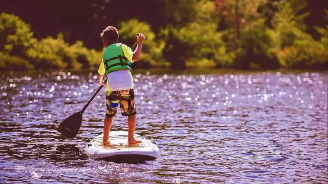 boy paddle boarding in lake